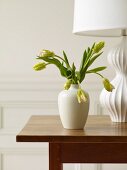 White Vase of Flowers on a Table with a White Lamp