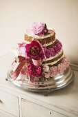 Mehrstöckige Hochzeitstorte verziert mit rosa Blüten & Schleife