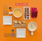 Cheese fondue with bread, potatoes, plates and fondue forks (view from above)
