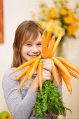 Smiling girl holding bunch of carrots