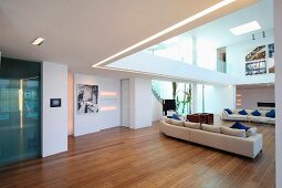 Sofagarnitur auf Holzfussboden in offenem Designer Wohnraum und Blick auf Galerie