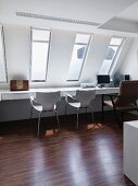 Home office an langem Arbeitstisch unter schlitzförmigen Dachflächenfenstern