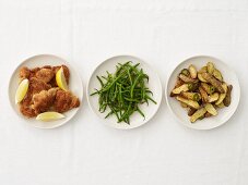 Panierte Hühnerbrust, grüne Bohnen & Kartoffeln auf drei Tellern