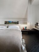 Hellgraue Tagesdecke auf Doppelbett in modernem Schlafzimmer mit dunklem Fischgrätparkett