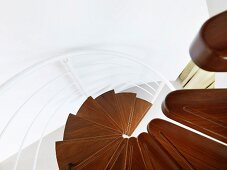 Blick auf moderne Wendeltreppe mit Holzstufen und weißem Metallgeländer