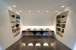 Arbeitsbereich mit Schalenstühlen auf hochglänzendem Steinboden und futuritische Raumteiler mit integriertem Regal