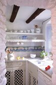 Nostalgic, Mediterranean kitchen with wooden cupboards and wall-mounted shelves with lace trim
