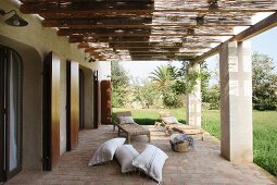 Terrasse mit Pergola auf Betonstützen vor mediterranem Haus und Blick in Garten