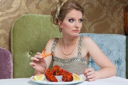 Woman in evening gown eating lobster