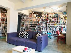 Purple sofa in front of floor-to-ceiling book shelves which cover all the walls of a modern living room