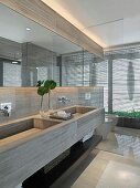 Custom made stone vanity with two basins and glass partition wall in front of a toilet