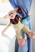 Monkey soft toy as humorous curtain tie-back in child's bedroom