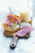 Gegrillter Käse im Speckmantel, Salamischeiben und Harzer Käse auf Holzbrett