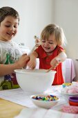 Young boy and girl mixing ingredients for cupcakes in a bowl
