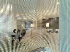 Glaswand mit geöffneter Jalousie und Blick ins moderne Büro