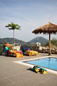 Colourful towels on loungers on terrace next to swimming pool (Villa Octavius, Lefkas, Greece)