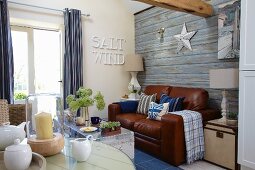 Maritime-style living room with leather sofa against wall with wood-effect wallpaper