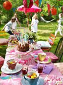 A birthday table in the garden with children playing in the background