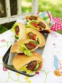 Pita breads filled with meat patties, salad, sweetcorn, cucumber and tomato