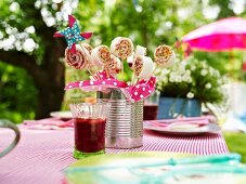 Sweet sandwich 'lollipops' and a glass of apple punch on a table outdoors