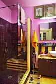 Dark purple shower cubicle in idiosyncratic bathroom with yellow accents and gold-painted door