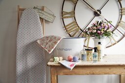 Laundry utensils on rustic wooden table below vintage wall clock