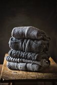 Five Grey Sweaters Stacked on a Wooden Table