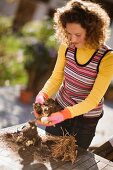 Junge Frau bei der Gartenarbeit im herbstlichen Garten