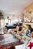Two Rococo armchairs in front of disused fireplace niche in bedroom crammed with furniture
