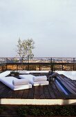 Holzpodest mit Liegen auf Dachterrasse mit Blick über Stadt