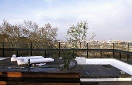 Loungers on a wooden podium on a roof terrace with a view over the city