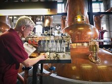 Worker checking whisky in distillery
