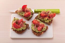 Crostini topped with guacamole, ham and cherry tomatoes