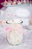 A jar of mini marshmallows decorated with a pink ribbon