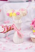 Three cake pops decorated with sugar roses in a vase