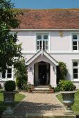 Grand entrance of country residence with planted amphorae flanking gravel path