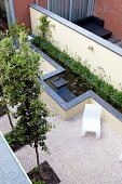 Geometrisch angelegter Garten mit quadratischen Beeten und einem langgezogenen Wasserbecken entlang der Gartenmauer
