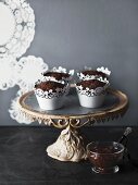 Schokoladenmuffins in verzierten Förmchen auf Kuchenständer