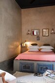 Mirrors above bed with storage compatments and lit bedside lamp in Moroccan home