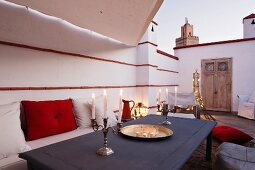 Lit candles and daybed on roof terrace of Marrakesh medina home