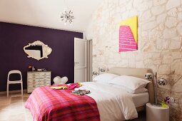Schlafzimmer mit Sputnik- Deckenleuchte und buntem Pop-Art-Bild an Natursteinwand