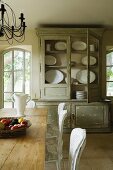 Distressed crockery cabinet with open back door and wooden kitchen table in Provence country house