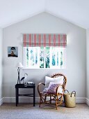 Cozy bamboo chair with adjoining tray table under window with striped roller blind