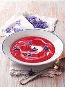 Beetroot soup with blue edible flowers
