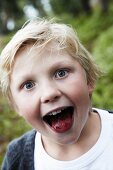 A boy sticking out his tongue which has been coloured with blueberries