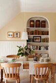 Wandnische mit Rundbogen als Bücherwand in freundlichem Esszimmer mit hellen Holzmöbeln