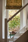 Blick von der Treppe in ein kleines Alkoven mit gemustertem Stoffrollo am Fenster
