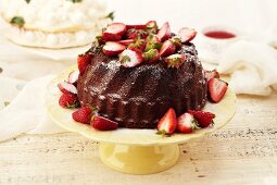 Schokoladennapfkuchen mit frischen Erdbeeren auf einer Kuchenplatte