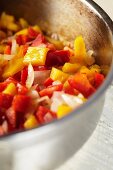 Gehackte Zwiebeln und rote und gelbe Paprika in einem Topf