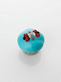 A turquoise cupcake decorated with ladybirds